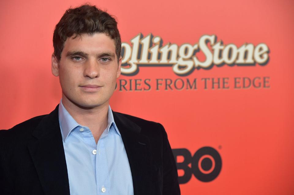 Photo of Gus Wenner in front of the Rolling Stone logo