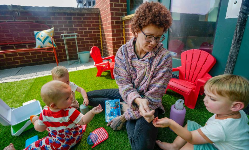 Kayla Janka, teacher, hands Ian Overton, right, and Francis O’Neil, in the stripes, snacks during lunch time  Tuesday, Aug. 8, 2023, at Le Village Cowork at 301 E. Reservoir Ave., Milwaukee. Le Village Cowork combines child care and a co-working space so working women can be near their children Tuesday, Aug. 8, 2023, Ebony Cox / Milwaukee Journal Sentinel