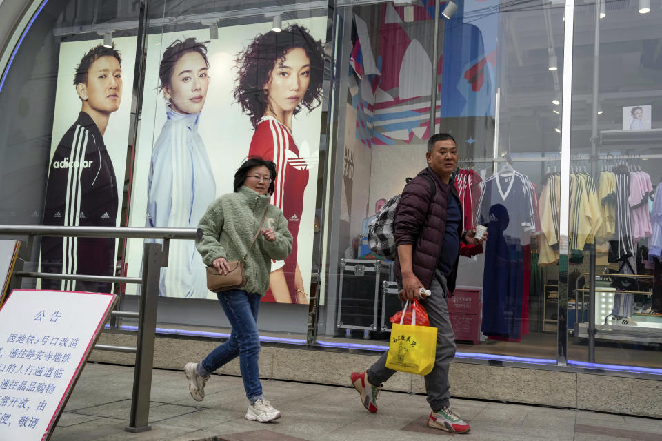 Shoppers walk by an apparel store in Shanghai on March 18, 2024. (AP Photo/Ng Han Guan)