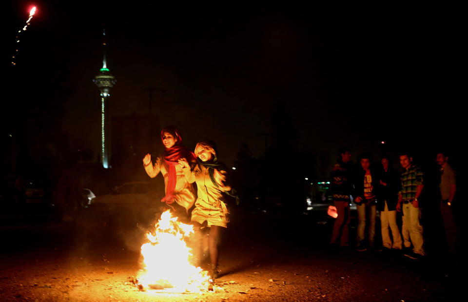 In this picture taken on Tuesday, March 18, 2014, two Iranian women jump over a bonfire during a celebration, known as “Chaharshanbe Souri,” or Wednesday Feast, marking the eve of the last Wednesday of the solar Persian year, in Pardisan park, Tehran, Iran. The festival has been frowned upon by hard-liners since the 1979 Islamic revolution because they consider it a symbol of Zoroastrianism, one of Iran’s ancient religions of Iranians. They say it goes against Islamic traditions. (AP Photo/Ebrahim Noroozi)