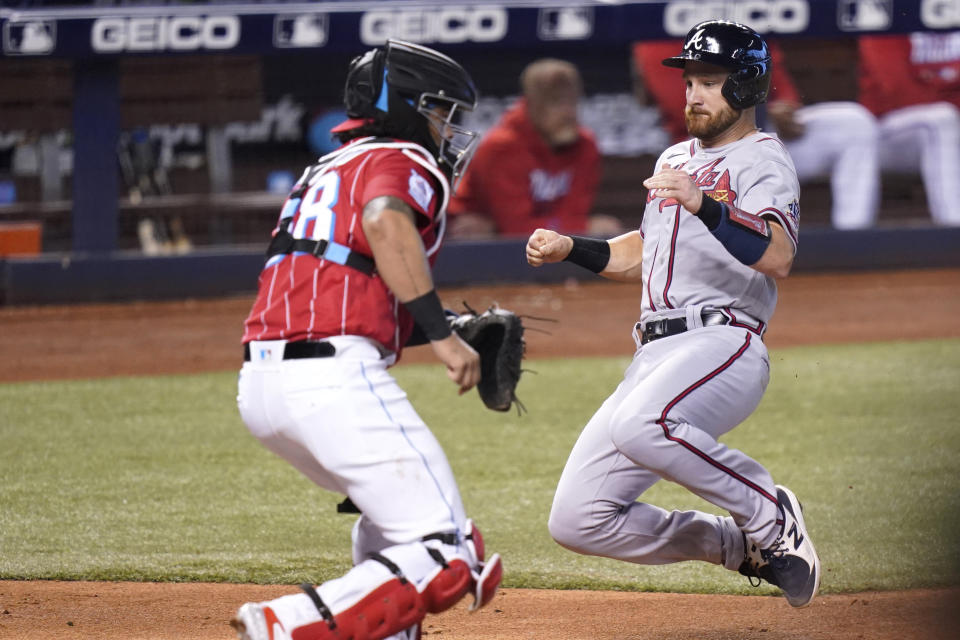 Atlanta Braves' Jonathan Lucroy, right, scores past Miami Marlins catcher Jorge Alfaro, left, on a single hit by Braves' Freddie Freeman during the third inning of a baseball game, Saturday, July 10, 2021, in Miami. (AP Photo/Lynne Sladky)