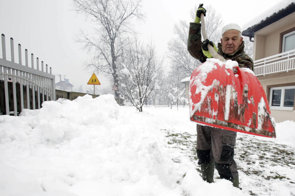 A Bosnian man shovels snow near Sarajevo, Bosnia, Monday, Dec. 17, 2018. Schools closed down for two days Monday in the central municipalities of Konjic and Jablanica, while trucks and heavy vehicles have been banned from some snow-covered roads. (AP Photo/Amel Emric)