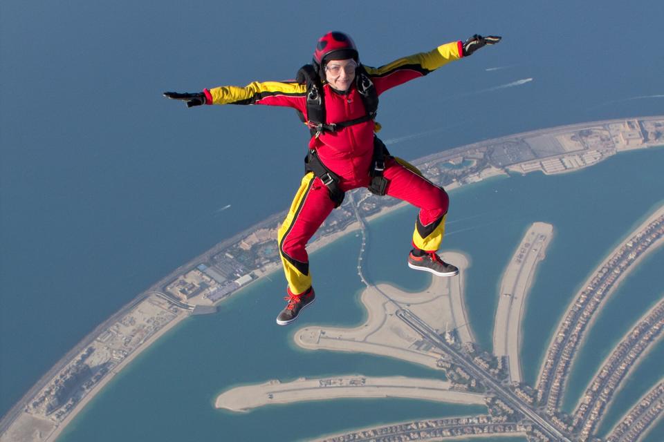 Skydiving woman free flying over Dubai palm