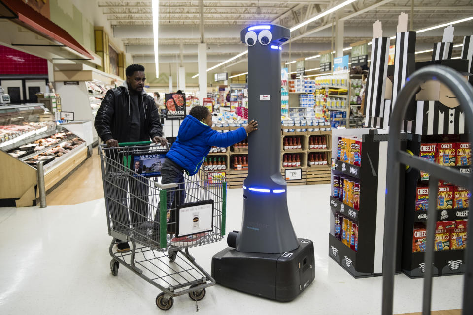 William Rucker and his grandson Justice, 4, say hello to a robot named Marty as it cleans the floors at a Giant grocery store in Harrisburg, Pa., Tuesday, Jan. 15, 2019. On Monday, the Carlisle-based Giant Food Stores announced new robotic assistants will be arriving at all 172 Giant stores by the middle of this year. The chain's parent company says it plans to eventually deploy the robots to nearly 500 stores. (AP Photo/Matt Rourke)