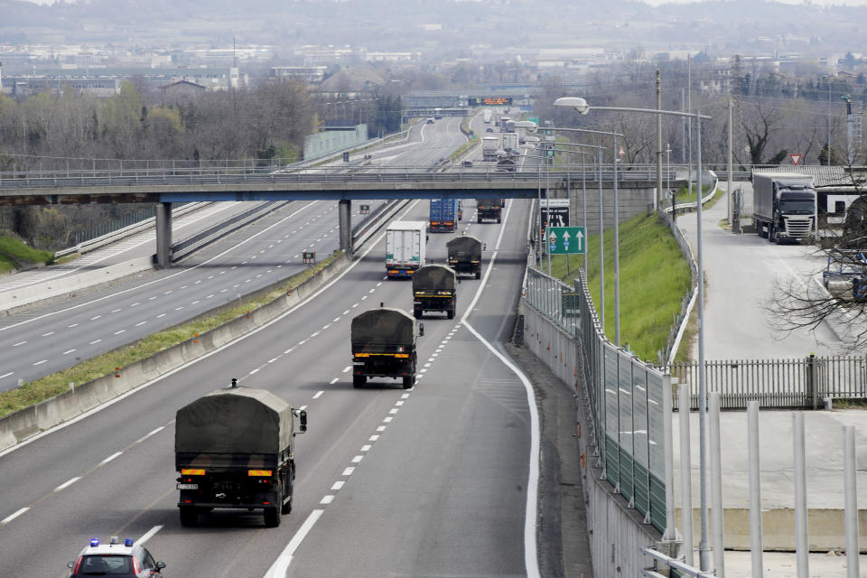 FILE - In this March 26, 2020 file photo, military trucks carrying coffins of deceased people are escorted on the highway next to Ponte Oglio, near Bergamo, one of the areas worst hit by the coronavirus infection, on their way from Bergamo cemetery to a crematory in some other location as the local crematory exceeded its maximum capacity. Italy is seeing a slight stabilizing in its confirmed coronavirus infections two weeks into the world’s most extreme nationwide shutdown, but the virus is taking its silent spread south after having ravaged the health care system in the north. The new coronavirus causes mild or moderate symptoms for most people, but for some, especially older adults and people with existing health problems, it can cause more severe illness or death. (AP Photo/Luca Bruno, file)