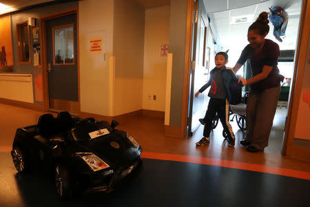 Jonathan Jauregui, 7, is helped from his wheelchair to an awaiting car as Rady Children's Hospital unveil a program that uses remote control cars, donated by the local police officers charity, to take young patients to the operating room, in San Diego, California, U.S. September 19, 2017. REUTERS/Mike Blake