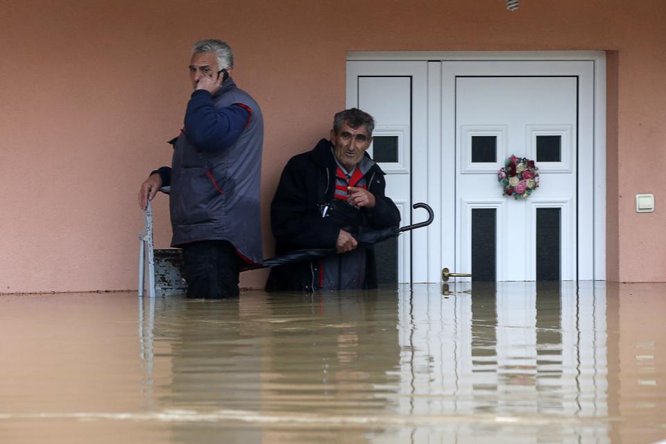 Two men stand in the waters in front of their flooded house as they wait to be evacuated in the town of Obrenovac, east from Belgrade May 16, 2014. (REUTERS/Marko Djurica)