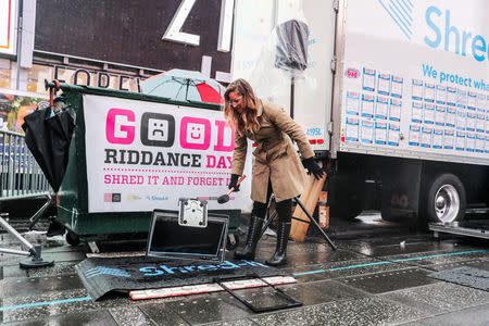 Allison Hagendorf mashes computer parts with a hammer during the National Good Riddance day ceremonial shredding of bad memories of 2018 in Times Square in the Manhattan borough of New York, U.S., December 28, 2018. REUTERS/Jeenah Moon