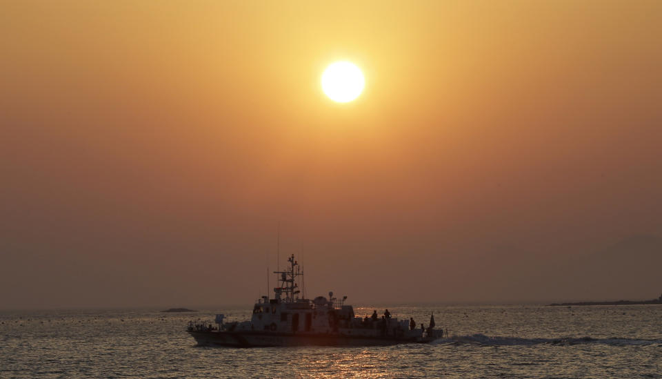 A South Korean Coast Guard ship sails at sunset near a port where relatives wait for news on their loved ones believed to have been trapped in the sunken ferry Sewol in Jindo, south of Seoul, South Korea, Tuesday, April 22, 2014. One by one, coast guard officers carried the newly arrived bodies covered in white sheets from a boat to a tent on the dock of this island, the first step in identifying a sharply rising number of corpses from a South Korean ferry that sank nearly a week ago. (AP Photo/Lee Jin-man)