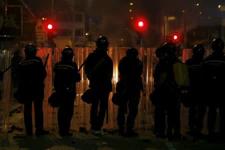 Riot police stand in front of a fire set by protesters at a junction at Mongkok shopping district in Hong Kong, China February 9, 2016. REUTERS/Bobby Yip