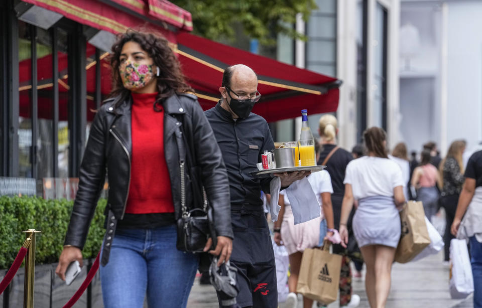 A waiter wearing a face mask to protect against coronavirus serves customers at the Champs Elysees avenue in Paris, Monday, July 12, 2021. France's President Emmanuel Macron is hosting a top-level virus security meeting Monday morning and then giving a televised speech Monday evening, the kind of solemn speech he's given at each turning point in France's virus epidemic. (AP Photo/Michel Euler)