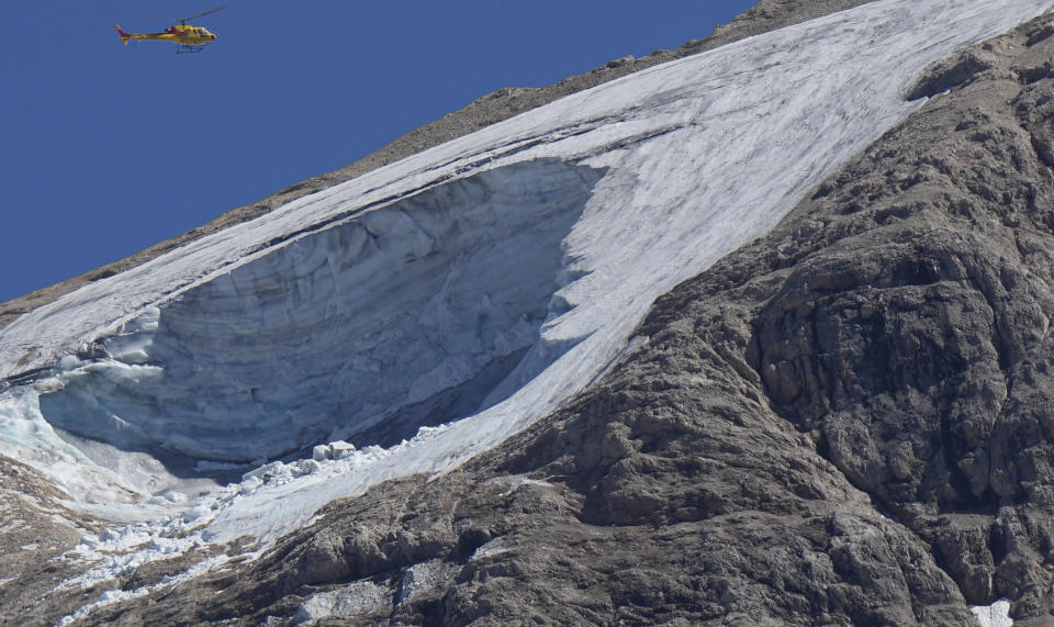 FILE - A rescue helicopter hovers over the Punta Rocca glacier near Canazei, in the Italian Alps in northern Italy, July 4, 2022, a day after a huge chunk of the glacier broke loose, sending an avalanche of ice, snow, and rocks onto hikers. Italy was enduring a prolonged heat wave before a massive piece of the Alpine glacier broke off and killed hikers on Sunday and experts say climate change will make those hot, destabilizing conditions more common. (AP Photo/Luca Bruno, File)