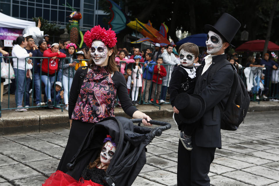 A family dressed as Catrinas parade down Mexico City's iconic Reforma avenue during celebrations for the Day of the Dead in Mexico, Saturday, Oct. 26, 2019. (AP Photo/Ginnette Riquelme)