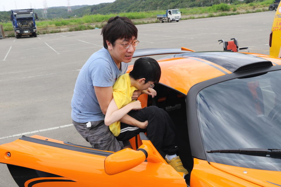小樂的父親抱著他坐上跑車。   圖：新北市社會局提供