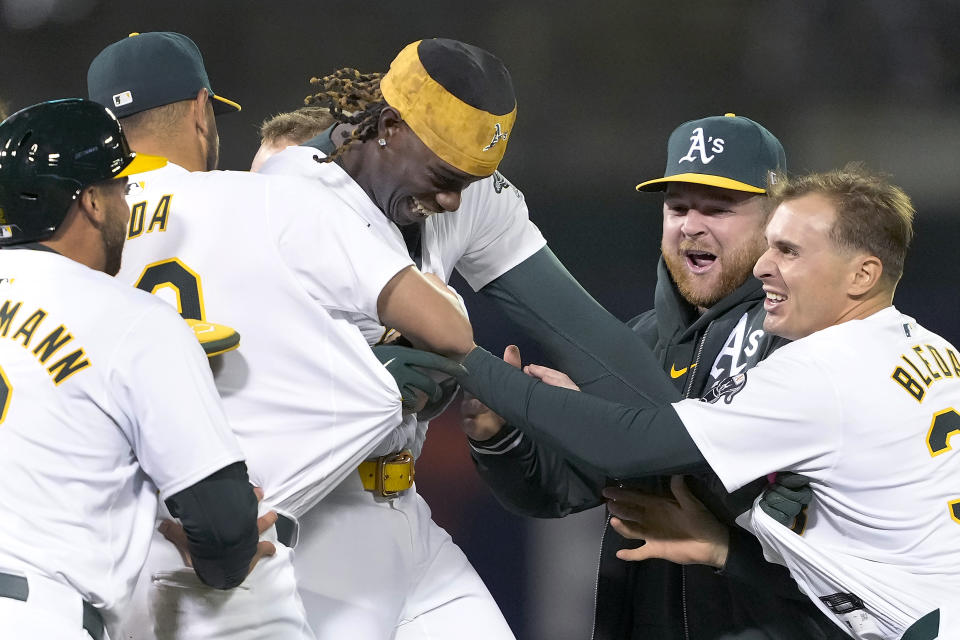 Oakland Athletics' Lawrence Butler, center, celebrates with teammates after hitting a single to drive in the winning run during the 10th inning against the Washington Nationals in a baseball game in Oakland, Calif., Friday, April 12, 2024. (AP Photo/Tony Avelar)