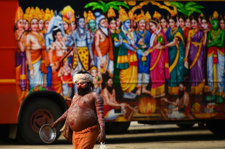 <p>An Indian sadhu walks past a vehicle bearing the images of Indian Hindu deities in Allahabad on March 6, 2016. </p>