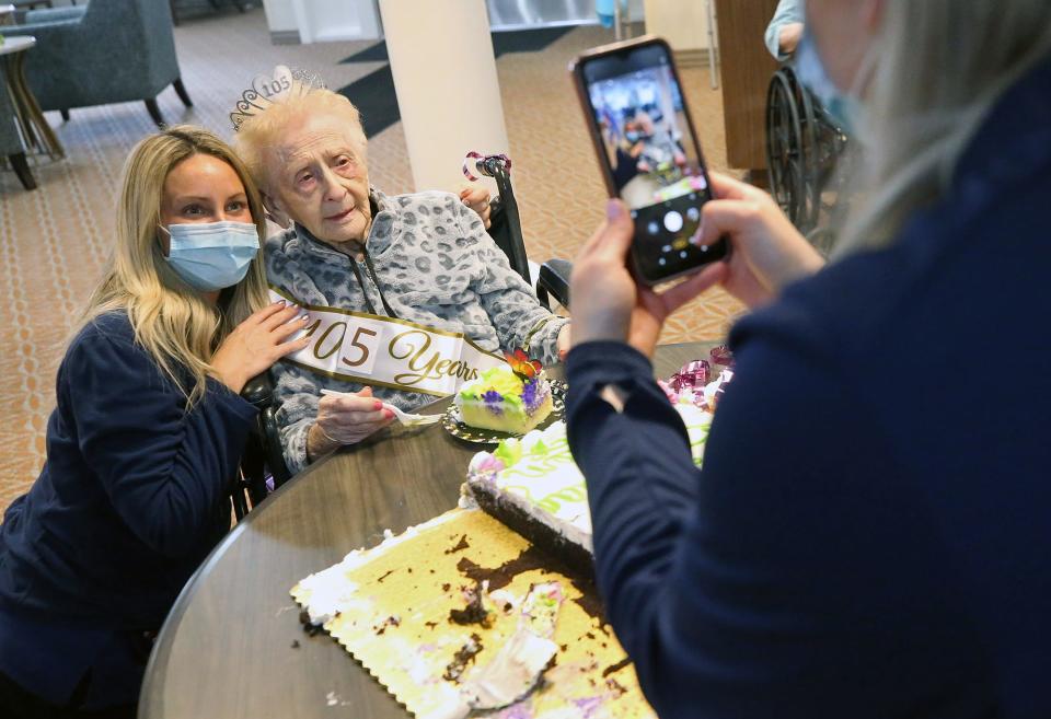 Meghan Payne, a caregiver at The Landing of Stow , left, has her picture taken with Helen Molnar during a party celebrating Molnar's 105th birthday.