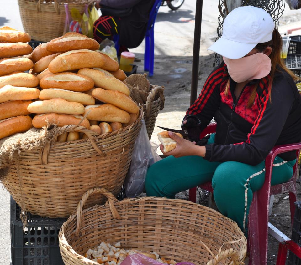 a person sitting by a basket of baguettes