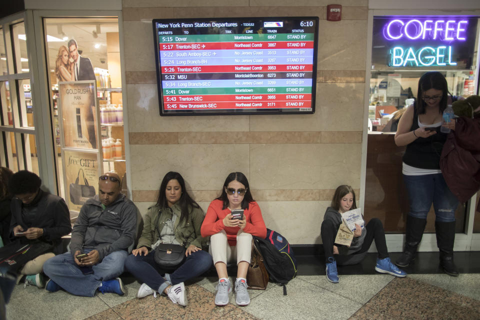 Evening rush hour commuters wait for trains sitting under the departures board announcing that all trains are on stand by at Penn Station, Friday, April 14, 2017, in New York. A New Jersey Transit train with about 1,200 passengers aboard is stuck in a Hudson River tunnel between New York and New Jersey. Authorities say the Northeast Corridor train became disabled Friday due to an Amtrak overhead power problem. (AP Photo/Mary Altaffer)