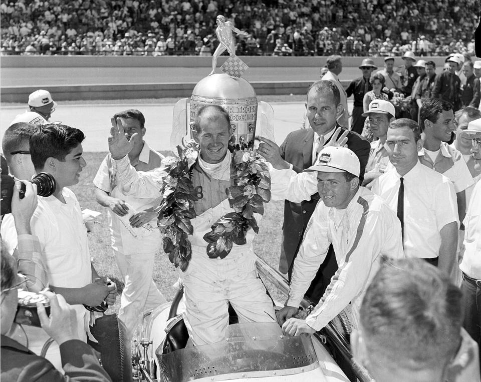 FILE - Parnelli Jones, center, celebrates his victory in the Indianapolis 500 auto race in front of the Borg-Warner Trophy at Indianapolis Motor Speedway in Indianapolis on May 30, 1063. Jones died Tuesday, June 4, 2024, at Torrance (Calif.) Memorial Medical Center after a battle with Parkinson's disease, his son said. Jones was 90. (AP Photo, File)