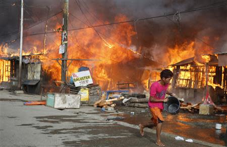 A man runs to fetch water to douse burning houses in a residential district, caused by a firefight between government soldiers and Muslim rebels from the Moro National Liberation Front (MNLF), in Zamboanga city in southern Philippines September 12, 2013. REUTERS/Erik De Castro