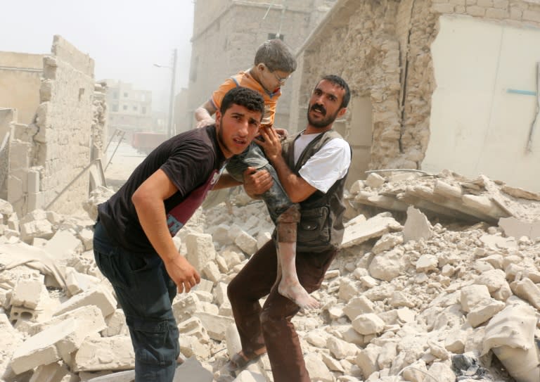 Syrians carry a wounded child in the rubble of buildings following a barrel bomb attack on the Bab al-Nairab neighbourhood of the northern Syrian city of Aleppo on August 25, 2016