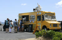 People line up at a food truck parked near Waikiki Beach in Honolulu, Monday, May 23, 2022. A COVID surge is under way that is starting to cause disruptions as schools wrap up for the year and Americans prepare for summer vacations. Case counts are as high as they've been since mid-February and those figures are likely a major undercount because of unreported home tests and asymptomatic infections. But the beaches beckoned and visitors have flocked to Hawaii, especially in recent months. (AP Photo/Caleb Jones)