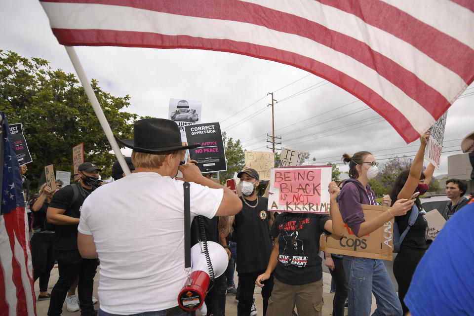 Demonstrators argue with Bruce Boyer, left, who was using a megaphone to ask protesters questions about why they were there during the protest, Saturday, June 6, 2020, in Simi Valley, Calif., over the death of George Floyd. Floyd died after he was restrained in police custody on Memorial Day in Minneapolis. (AP Photo/Mark J. Terrill)