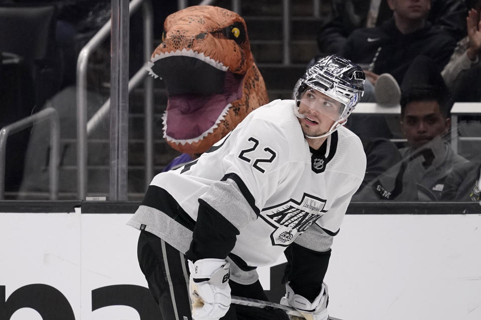 A fan wearing a dinosaur costume sits in the stands as Los Angeles Kings left wing Kevin Fiala skates by during the second period of an NHL hockey game against the Toronto Maple Leafs Saturday, Oct. 29, 2022, in Los Angeles. (AP Photo/Mark J. Terrill)