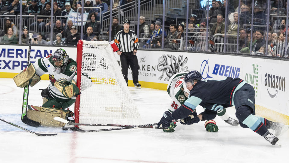 Minnesota Wild goalie Marc-Andre Fleury, left, knocks away a shot by Seattle Kraken forward Ryan Donato, right, during the second period of an NHL hockey game Friday, Nov. 11, 2022, in Seattle. (AP Photo/Stephen Brashear)