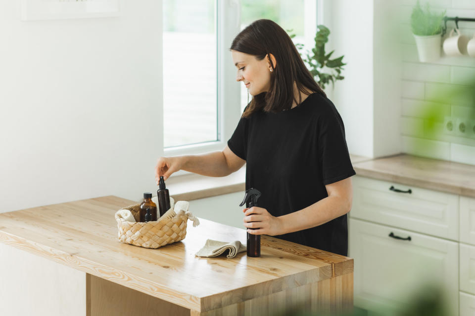 Woman putting small bottles in a wicker tray on a countertop