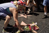 A fan honors actor Olivia Newton-John with flowers on Newton-John's Hollywood Walk of Fame star in Los Angeles, Monday, Aug. 8, 2022. Newton-John, the Grammy-winning superstar who reigned on pop, country, adult contemporary and dance charts with such hits as "Physical" and "You're the One That I Want" has died. She was 73. (AP Photo/Damian Dovarganes)