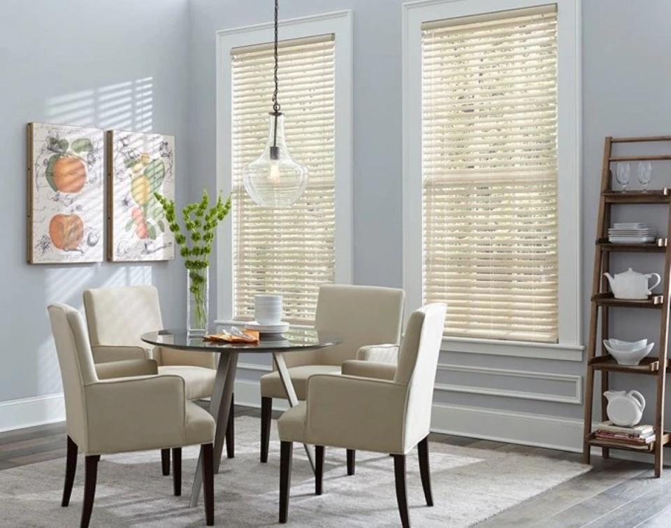 Two tall windows with aluminum blinds in a small dining room