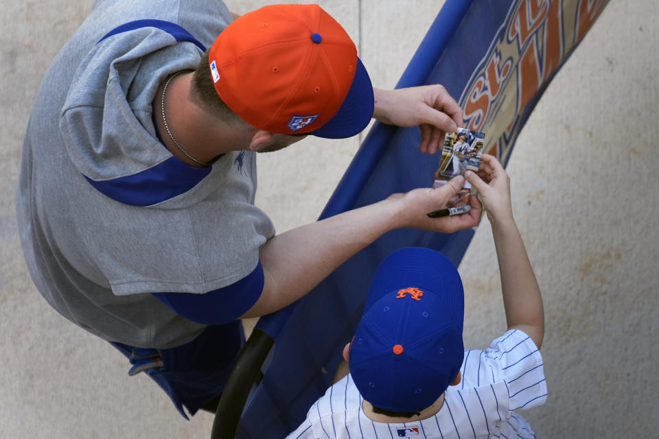 New York Mets' Pete Alonso, left, looks at an autograph he signed for a young fan during a spring training baseball workout Saturday, Feb. 17, 2024, in Port St. Lucie, Fla. (AP Photo/Jeff Roberson)