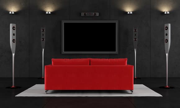 A home theater with a flat-screen TV and a red love seat.