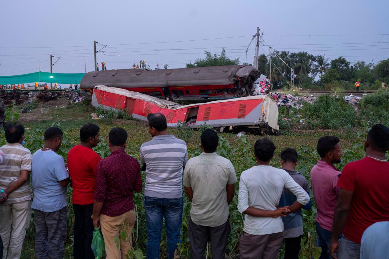 People gather Sunday to look at the mangled wreckage of the two passenger trains that derailed Friday in Balasore district, in the eastern state of Odisha, India.