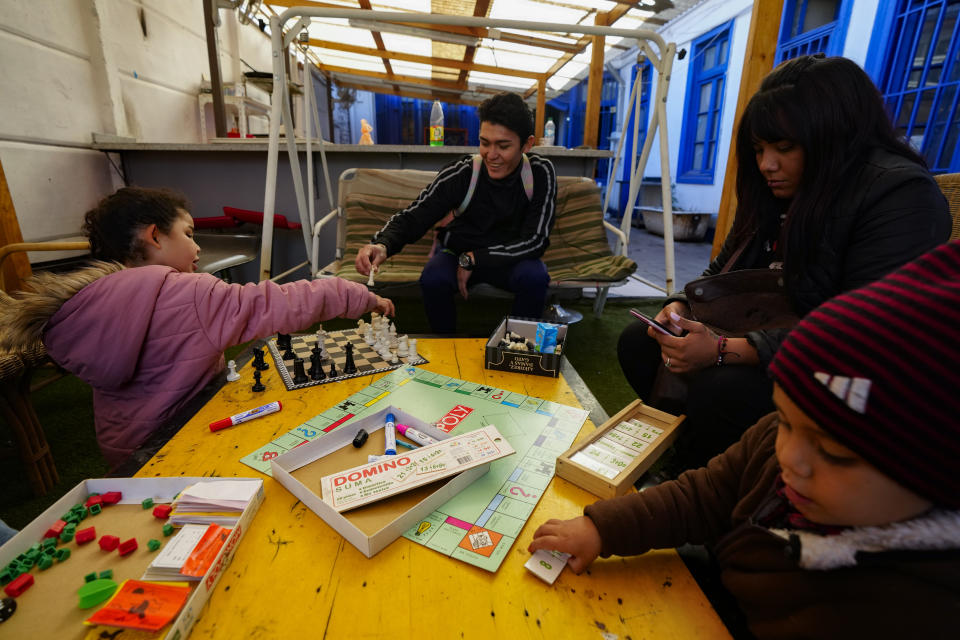 Karen Salazar, segundo por la derecha, y Luis Henrique, en el centro, una pareja de migrantes venezolanos, juegan con sus hijos Malin y Sebastián en el albergue "Nuestra Casa" en el barrio de Yungay de Santiago, Chile, el jueves 30 de mayo de 2024. Tras salir de Venezuela y encontrarse con una vida como migrantes insoportable en Colombia y luego en Ecuador, la familia se mudó a Chile. (AP Foto/Esteban Félix)