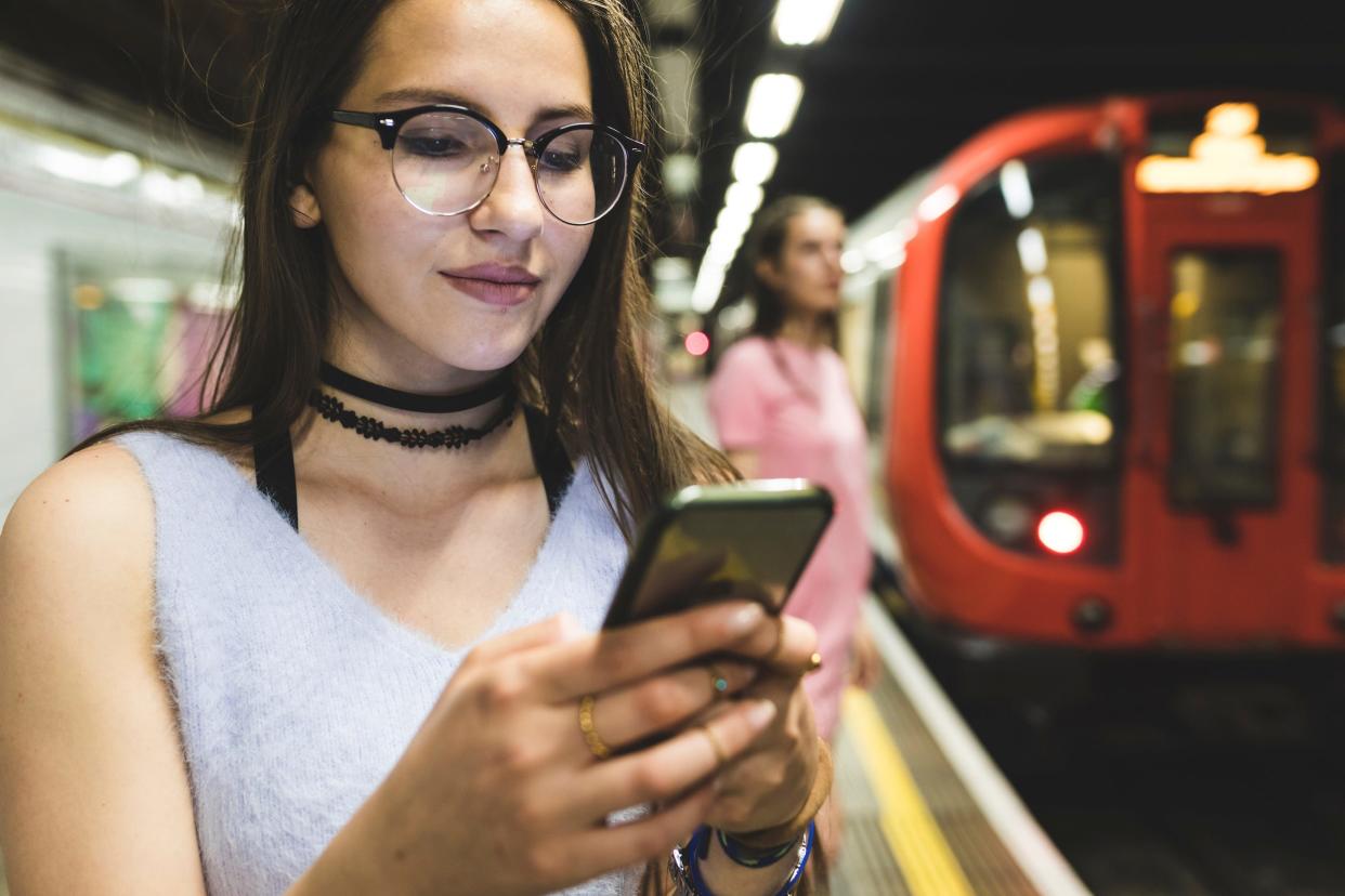 teen girl holding smartphone on subway