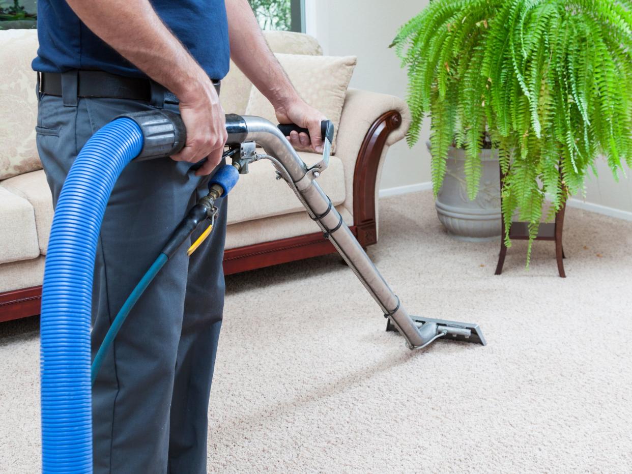 Man cleaning carpets in home