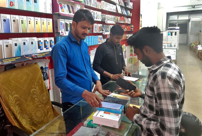 Customer checks a Samsung mobile phone before purchasing it, in a mobile store in Lucknow