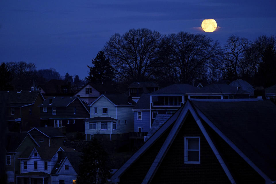 The moon sets behind homes in Pittsburgh, Thursday, March 17, 2022. Around the country, as child welfare agencies use or consider algorithmic tools like in Allegheny County, an Associated Press review has identified a number of concerns about the technology, including questions about its reliability and its potential to harden racial disparities in the child welfare system. (AP Photo/Matt Rourke)