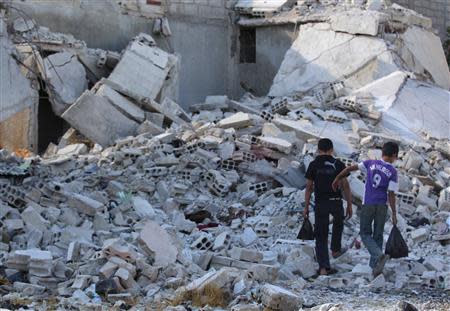 Boys walk amidst the rubble of damaged buildings in Duma neighbourhood of Damascus September 23, 2013. REUTERS/Bassam Khabieh