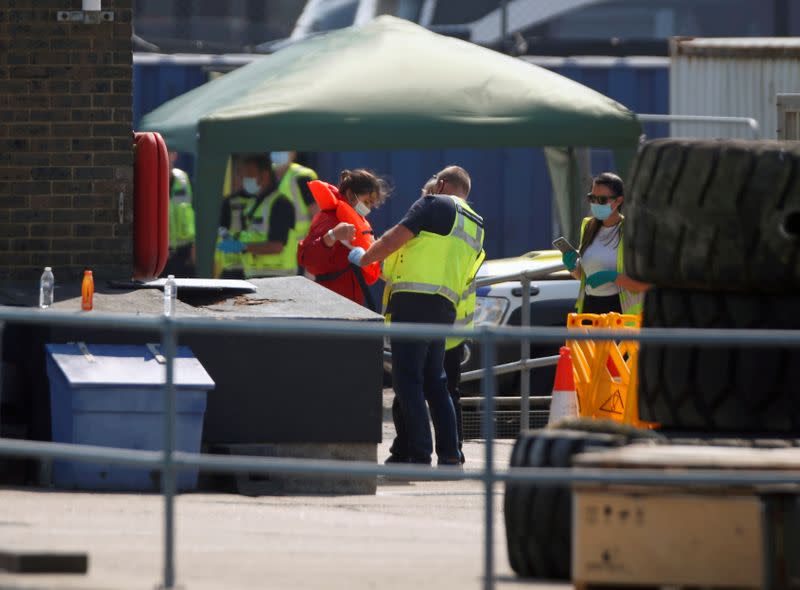 FILE PHOTO: Man helps a migrant woman as she got off of the Border Force's boat after arriving at Dover harbour, in Dover