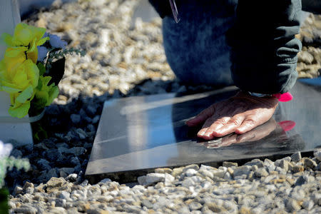 A relative of an Argentine soldier who died during the Falklands War touches his tombstone at Darwin cemetery, in the Falkland Islands, March 26, 2018. Argentine Presidency/Handout via REUTERS