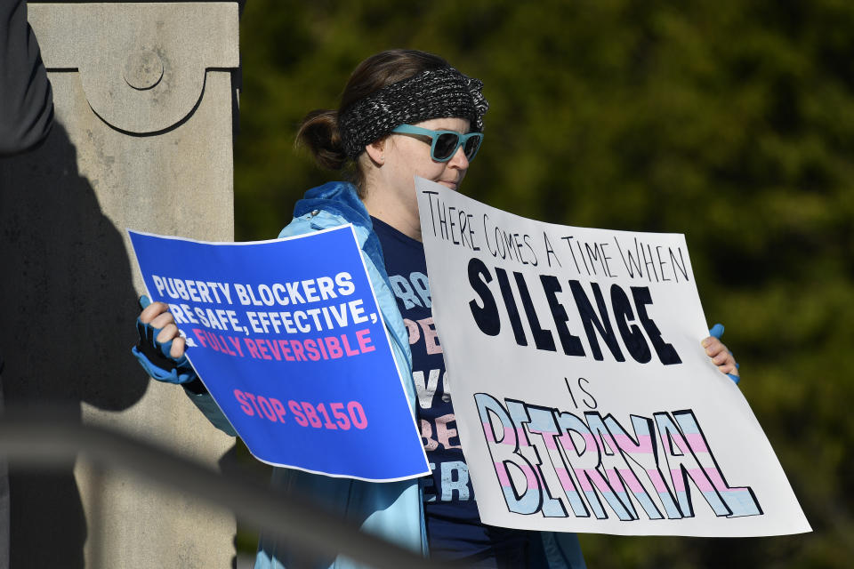 A protester holds up signs in opposition of Kentucky Senate bill SB150, known as the Transgender Health Bill on the lawn of the Kentucky State Capitol in Frankfort, Ky., Wednesday, March 29, 2023. (AP Photo/Timothy D. Easley)