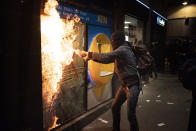 A protestor try to burn a bank branch after breaking the window following a protest condemning the arrest of rap singer Pablo Hasél in Barcelona, Spain, Saturday, Feb. 27, 2021. After a few days of calm, protests have again turned violent in Barcelona as supporters for a jailed Spanish rapper went back to the streets. (AP Photo/Emilio Morenatti)