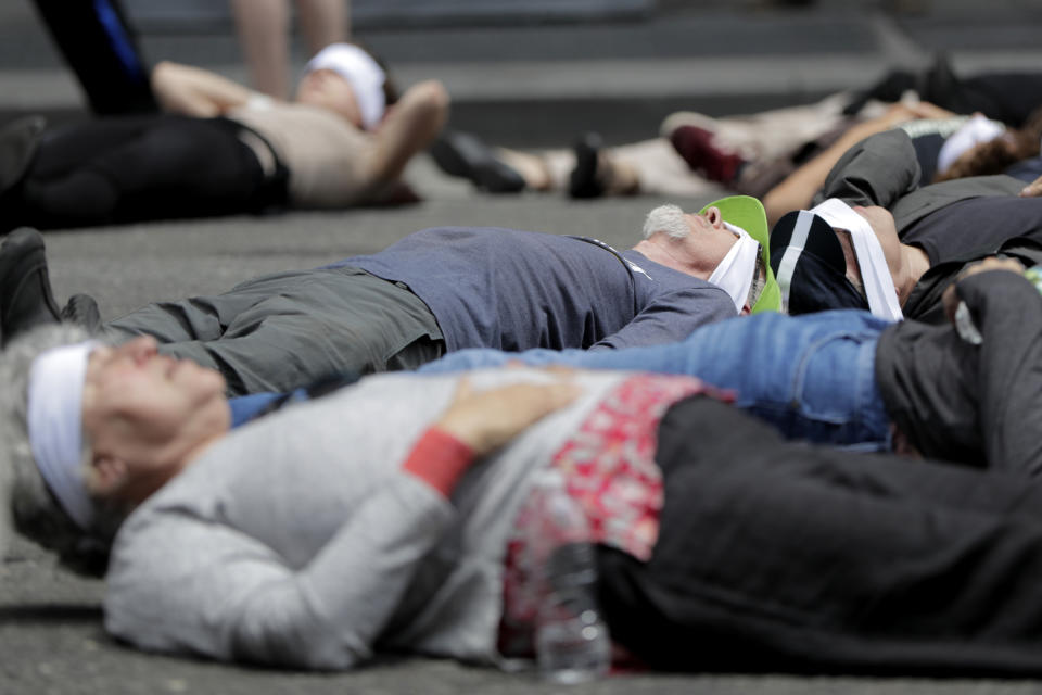 Activists lie in the middle of 8th Avenue in front of the New York Times building during a climate change rally, Saturday, June 22, 2019, in New York. Activists were taking into custody after blocking traffic during a sit-in to demand coverage of climate change by the newspaper. (AP Photo/Julio Cortez)