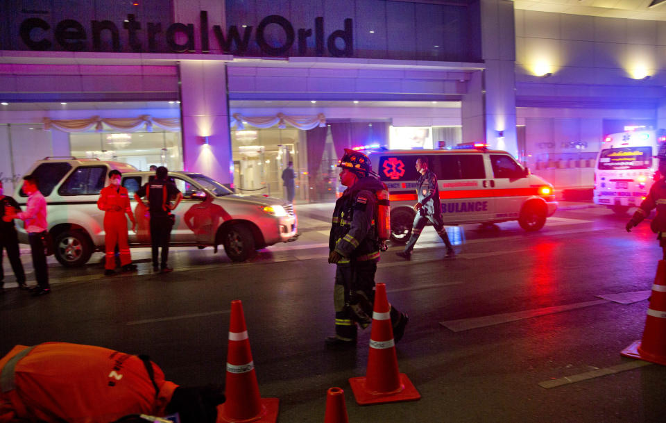 Firefighters and rescue workers stand outside the scene of a fire at the Central World mall complex in Bangkok, Thailand, Wednesday, April 10, 2019. A fire had broken out at the major mall complex in Thailand's capital, with initial reports from Thai emergency services saying it caused numerous fatalities. (AP Photo/Gemunu Amarasinghe)