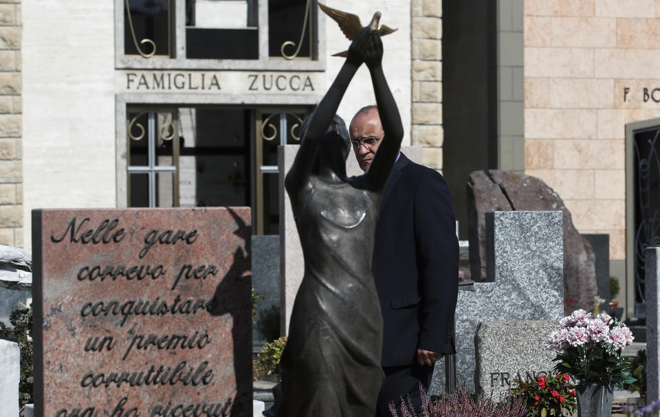 Rev. Mario Carminati walks behind tombstones in a cemetery in Casnigo, near Bergamo, Italy, Sunday, Sept. 27, 2020. As the world counts more than 1 million COVID victims, the quiet of everyday life and hum of industry has returned to Bergamo, which along with the surrounding Lombardy region was the onetime epicenter of the outbreak in Europe. But the memory of those dark winter days, and the monumental toll of dead they left behind, has remained with those who survived only to see the rest of the world fall victim, too. (AP Photo/Antonio Calanni)