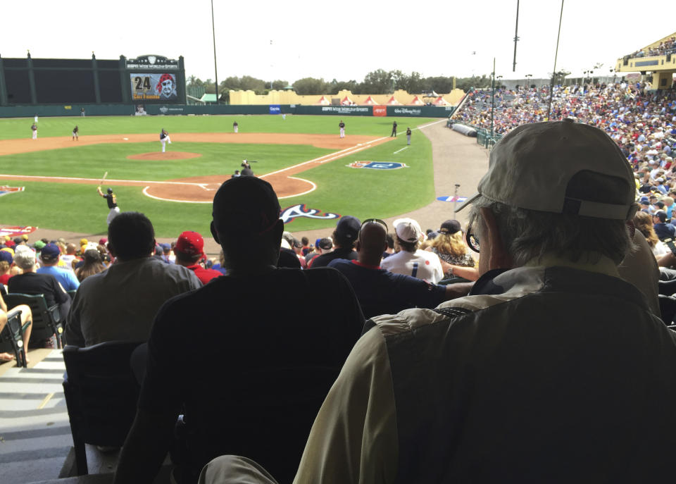 FILE - In this March 5, 2016, file photo, Tommy Giordano, right foreground, special assistant to the general manager of the Atlanta Braves, scouts a spring training baseball game between the Braves and the Pittsburgh Pirates, in Kissimmee, Fla. Tommy Giordano is dying. But do not let your heart be heavy. He’s going out like he lived for more than 93 years _ surrounded by family and friends, accompanied by overwhelming love and stories that will endure long after he’s gone. (AP Photo/Paul Newberry, File)